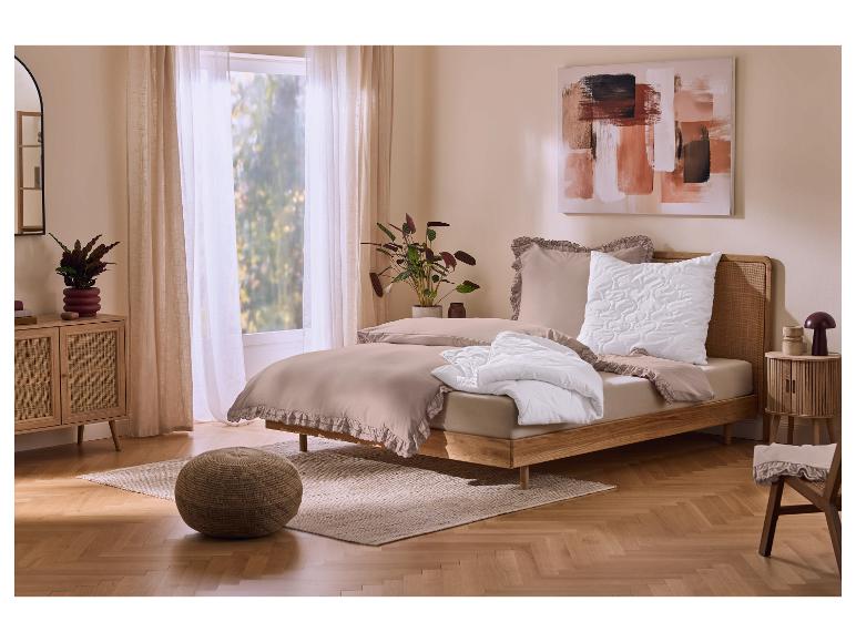 Schlafzimmer mit Holzbett, beiger Bettwäsche mit Rüschen und weißer Bettdecke.