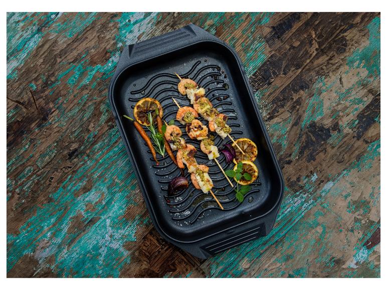 Gegrillte Garnelen- und Fischspieße mit Gemüse und Zitrone in einer Pfanne.