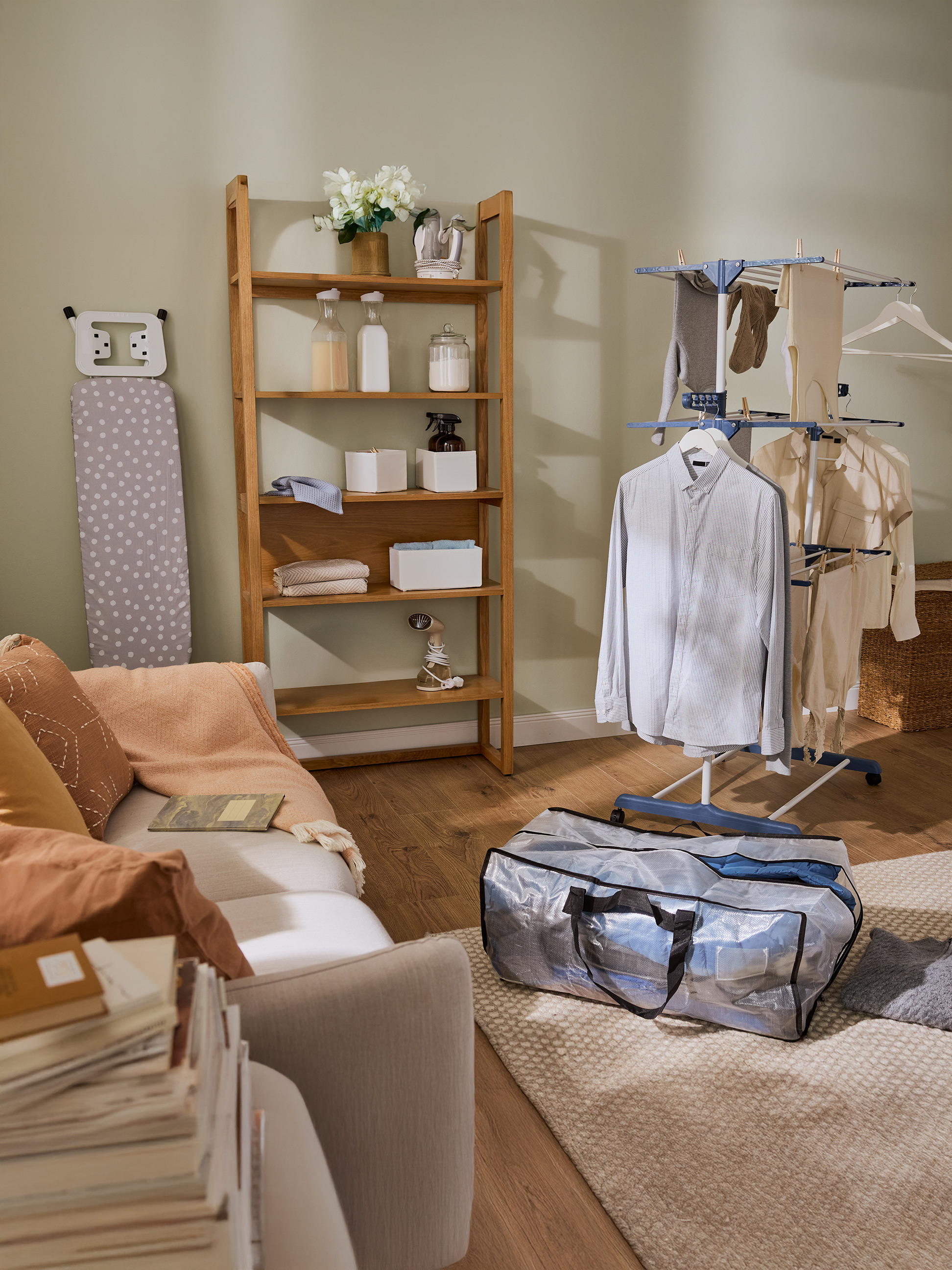 Waschküche mit Holzregal, Bügelbrett und Wäscheständer mit Kleidung.