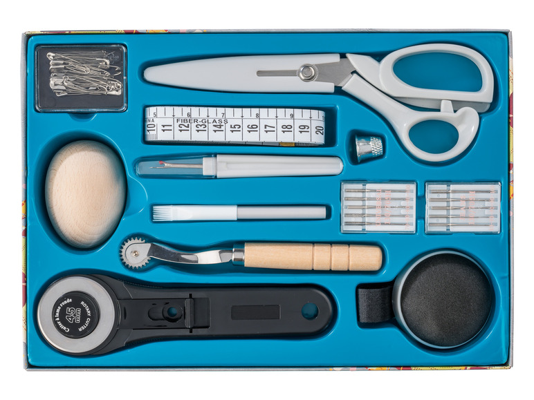 Ein Nähset mit Rollschneider, Schere, Nadeln und Maßband.