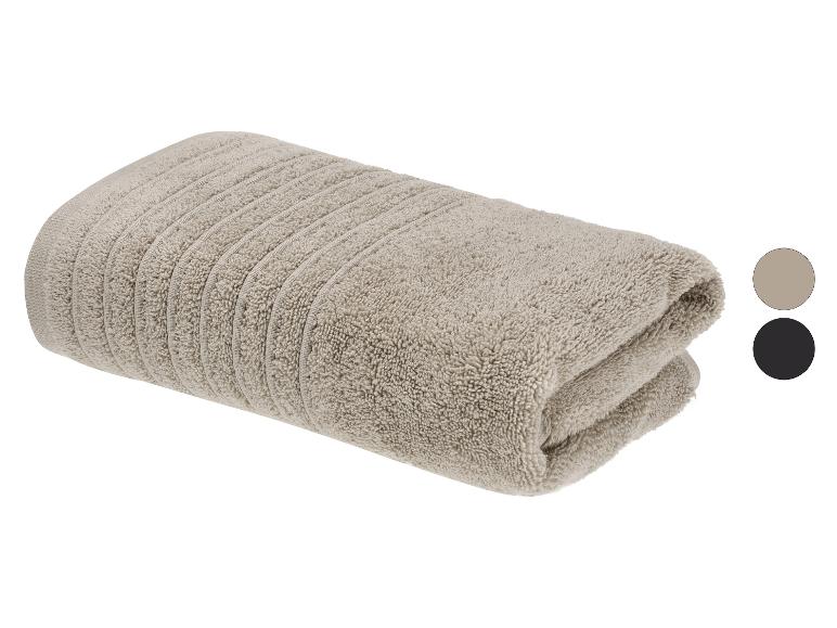 Gefaltetes beiges Handtuch mit gerippter Textur, zeigt zwei Farbmuster: Beige und Schwarz.