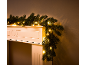 Weihnachtsgirlande mit warmweißen Lichtern auf einem weißen Kaminsims.