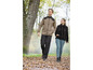 Mann und Frau laufen im Herbst durch den Wald, beide tragen eine Fleecejacke.