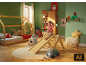 Mädchen rutscht auf Holzrutsche in Kinderzimmer mit Weihnachtsdekoration.