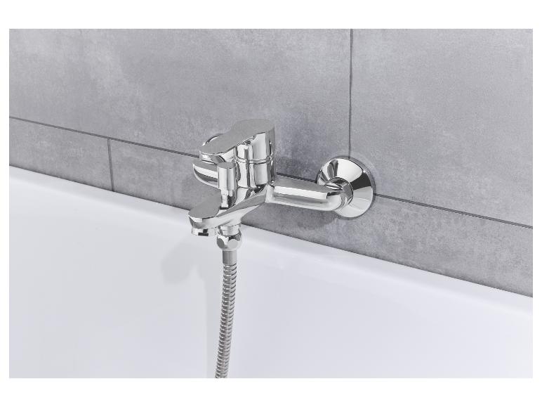 Chromarmatur für Badewanne mit Handbrause an grauen Fliesen.