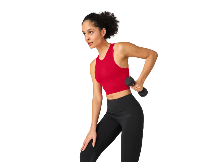 Frau trainiert mit Leggings und Sport-Top, Hantel in der Hand.