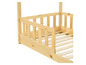 Ein Holzbett mit einem Seitenschutzgitter für Kinder.