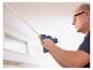 Mann verwendet LIVARNO® CG270 Akku-Klebepistole, um eine Leiste an der Decke zu befestigen.