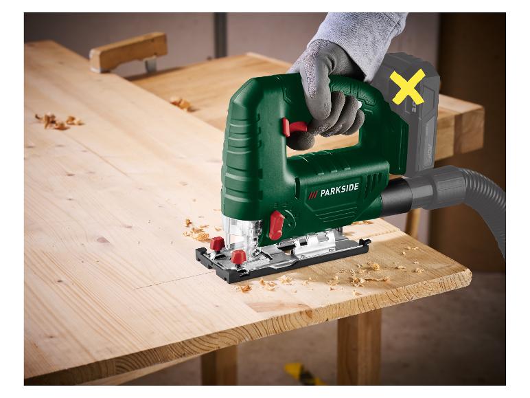 Akku-Stichsäge mit Staubsauger auf Holz, gehalten von einer Person mit Handschuh.