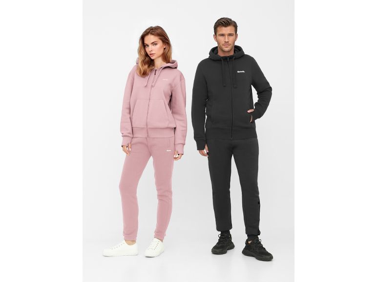 Mann und Frau in Kapuzenjacken und Jogginghosen, Frau in Rosa, Mann in Schwarz.