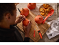 Person schnitzt Halloween-Kürbisse mit Schnitzwerkzeugen und Kernen.