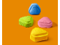 Vier bunte, dreieckige Bonbons auf orangefarbenem Hintergrund.