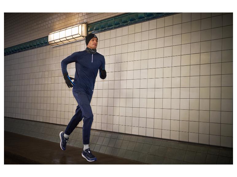 Mann läuft in einem Tunnel, trägt Kapuzenpullover, Hose und Laufschuhe.