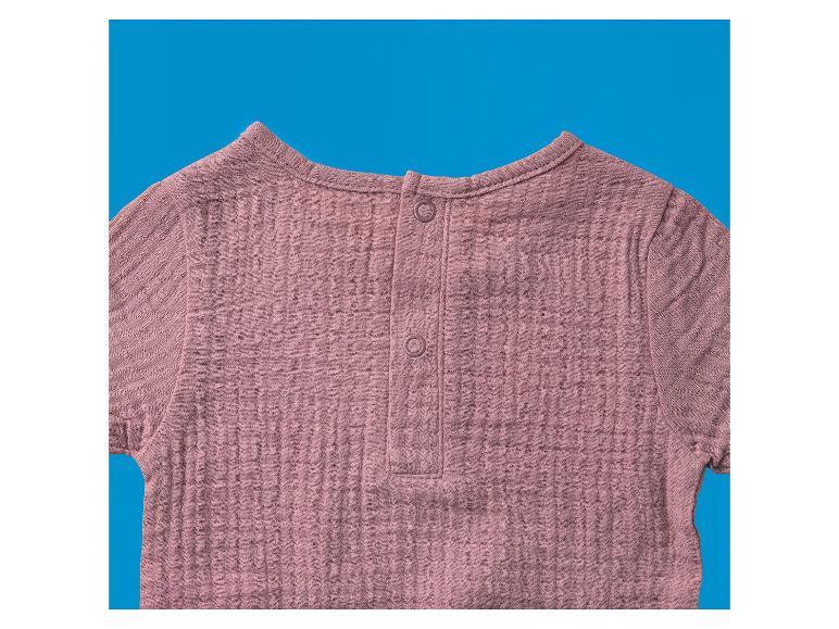 Rosa kurzärmliges Kinder-Oberteil mit Knöpfen am Rücken.
