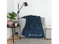 Dunkelblaue Decke auf einem grauen Sofa mit Lampe und Zimmerpflanze.