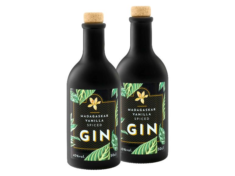 Zwei schwarze Flaschen Madagaskar Vanille Gewürz-Gin mit Etiketten mit grünen Blättern und gelben Blüten.