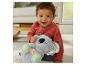 Glückliches Baby hält ein Plüsch-Koala-Spielzeug mit leuchtendem Bauch, sitzend auf einem Teppich.
