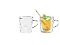 Zwei doppelwandige Glastassen, eine leer und eine gefüllt mit Tee, Zitrone, Minze und Strohhalm