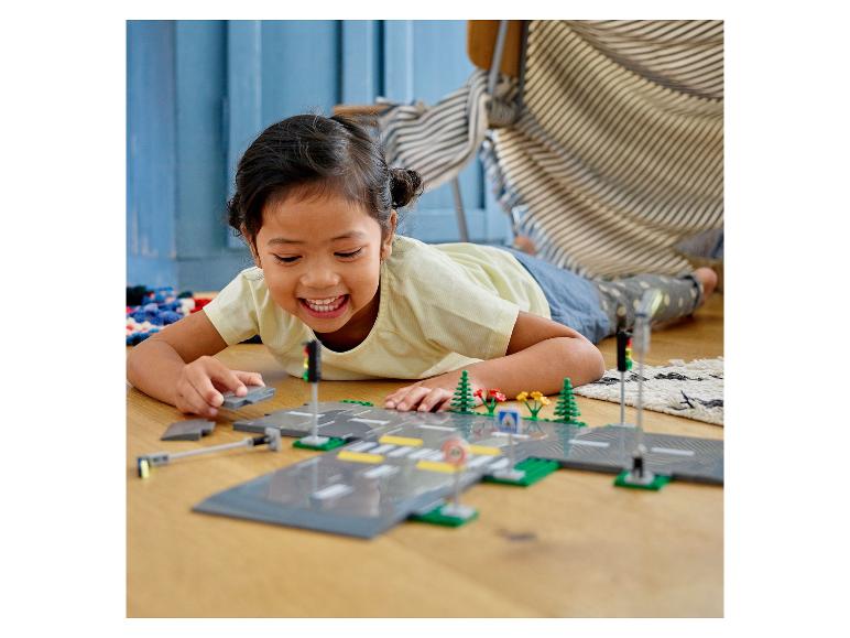 Kind spielt mit LEGO® City: Straßen, Ampeln und Pflanzen.