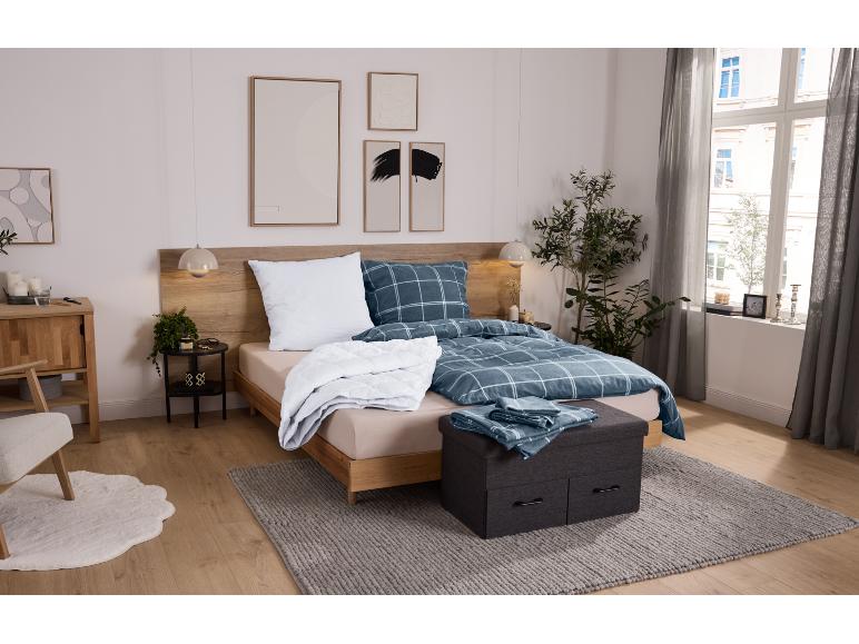 Gemütliches Schlafzimmer mit Holzbett, blauer karierter Bettwäsche und grauem Teppich.