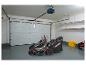 Rasenmäher in einer Garage mit Garagentor und Regalen.