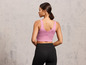 Frau in einem rosa Sport-BH und schwarzen Leggings.