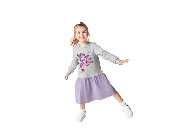 Ein Mädchen trägt ein graues Kleid mit einem Pferde-Print und einem lila Rock.