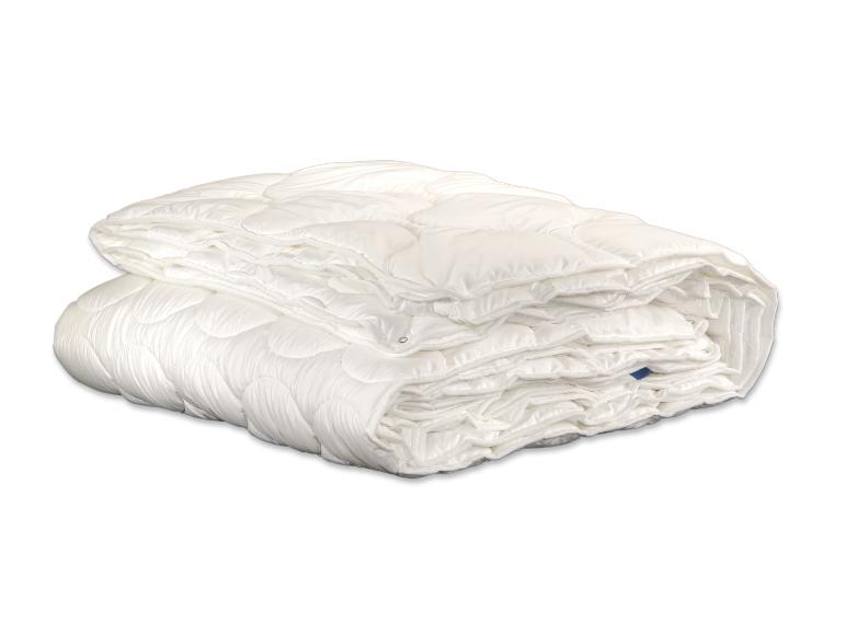 Eine weiße gesteppte Bettdecke oder Steppdecke, ordentlich gefaltet und gestapelt auf weißem Hintergrund.