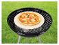 Pizza auf Pizzastein auf Holzkohlegrill auf Rasen.