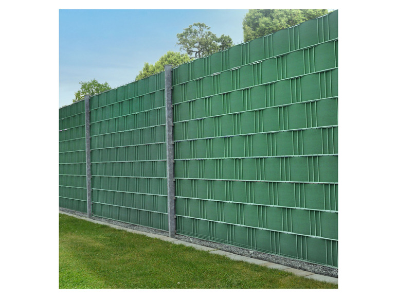 Ein grüner Metallzaun mit einem gewebten Muster.