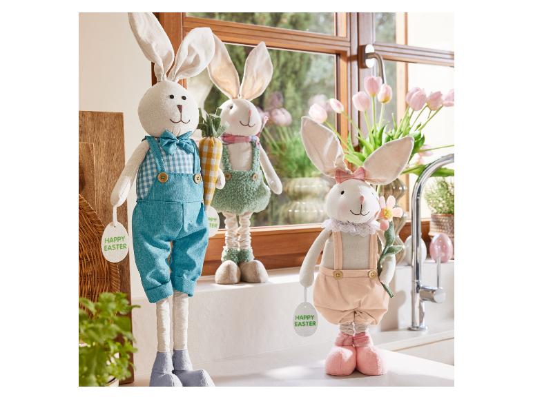 Drei Osterhasen in verschiedenen Outfits mit einem Osterei.