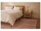 Schlafzimmer mit hellem Holzbett, weißer Bettwäsche und rosa Teppich