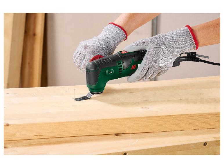 Person mit Handschuhen entfernt mit einem Multifunktionswerkzeug einen Nagel aus einem Holzbrett.