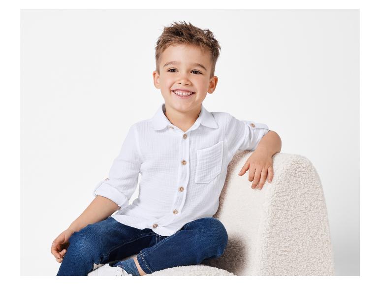 Lächelnder Junge in weißem Hemd und Jeans.