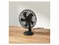 Schwarzer Tischventilator auf Holztisch.