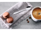 Kaffee mit Macarons, Löffel und Kaffeebohnen auf einem Leinentuch.