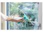 Eine Hand reinigt ein schaumiges Fenster mit einem türkisen Fensterabzieher.