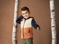 Ein Junge trägt eine orange-beige-blaue Hello Mini Jacke.