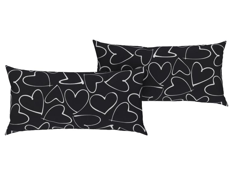 Zwei schwarze Kissen mit weißen Herzen.