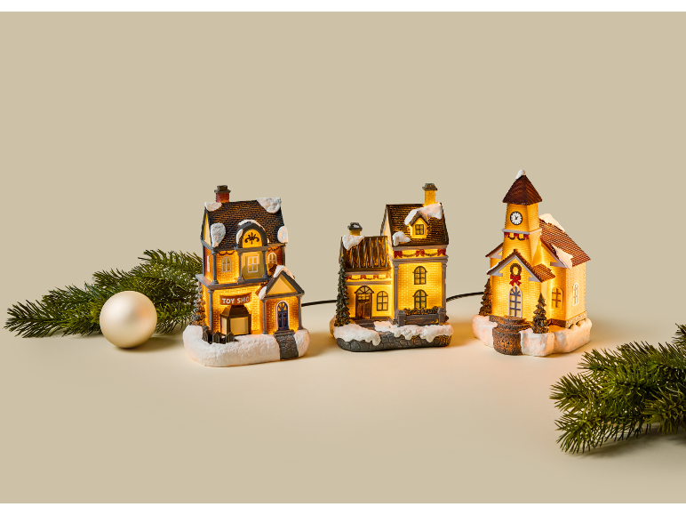 Beleuchtetes Weihnachtsdorf mit Häusern, Kirche und Tannenzweigen