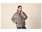Frau in Leoparden-Pufferjacke und Jeans, posiert mit Hand in der Tasche.