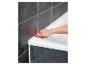 Eine Hand verwendet ein rotes Werkzeug, um Dichtmittel um eine weiße Badewanne aufzutragen.