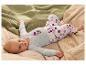 Baby in hellblauem Body mit Schleifen und gepunkteter Hose, auf Decken liegend.