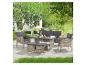 Rattan-Gartenmöbel-Set mit Sofa, zwei Sesseln, Tisch und zwei Hockern auf einer Terrasse.