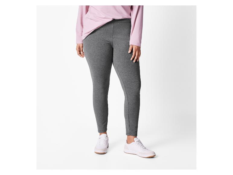 Eine Frau trägt ein rosa Langarmshirt und graue Leggings mit weißen Sneakern.