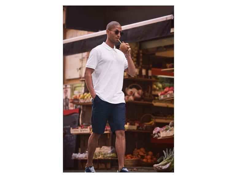 Weißes Polo, dunkelblaue Shorts und Kokosnuss: lässiger Sommerstil.