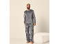 Mann in grauem Velours-Pullover und karierter Pyjamahose.