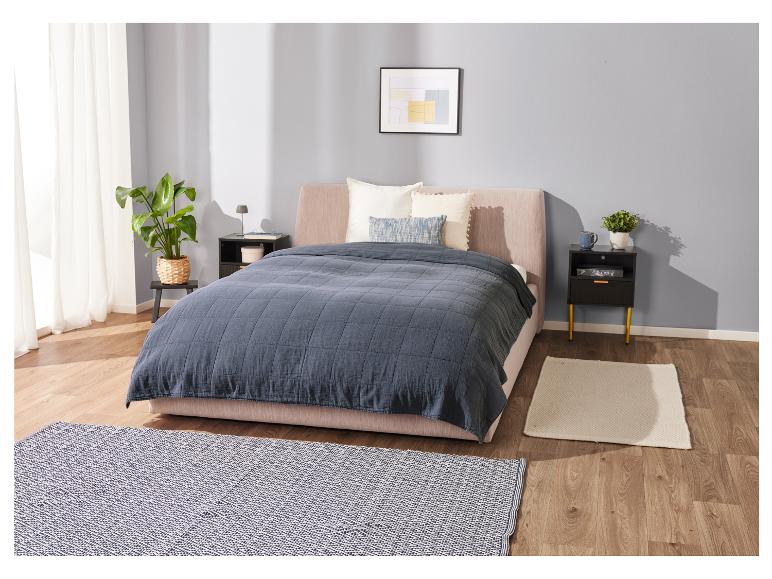 Bett, dunkelblaue Tagesdecke und Nachttische in einem modernen Schlafzimmer.