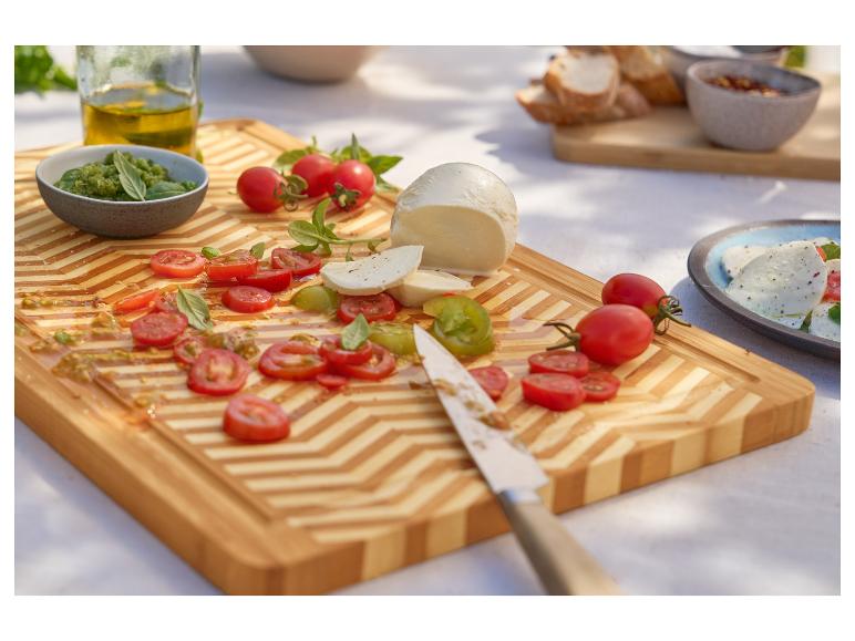 Mozzarella, Kirschtomaten und Pesto auf einem Bambusschneidebrett.