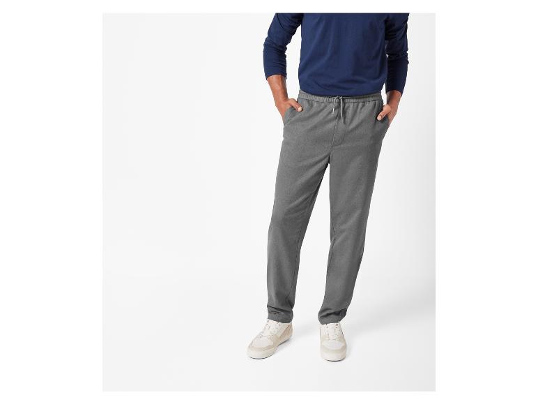 Mann trägt graue Hose mit weißen Sneakern.